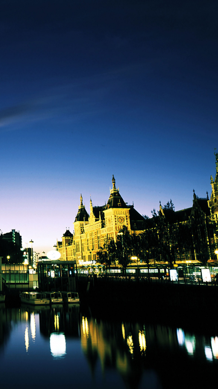 Cuerpo de Agua Cerca de Edificios Durante la Noche.. Wallpaper in 750x1334 Resolution