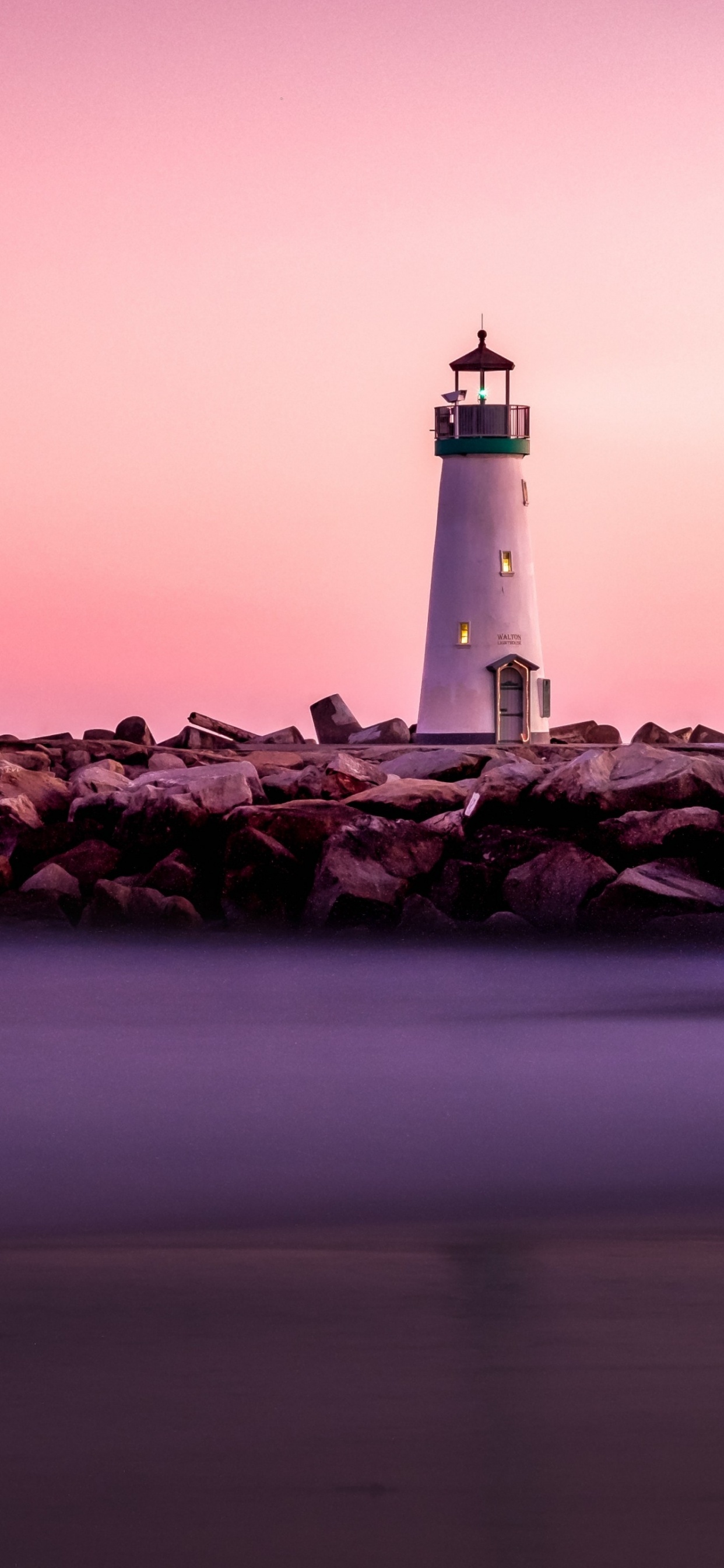 Phare Blanc Sur Une Formation Rocheuse Brune Près D'un Plan D'eau Pendant la Journée. Wallpaper in 1242x2688 Resolution