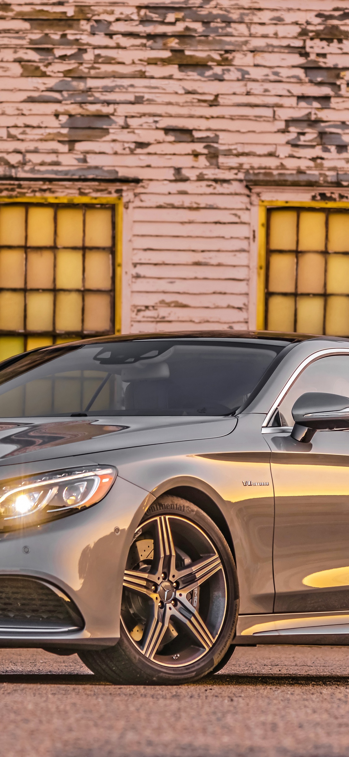 Silver Mercedes Benz Coupe Parked Beside Brown Brick Wall. Wallpaper in 1125x2436 Resolution