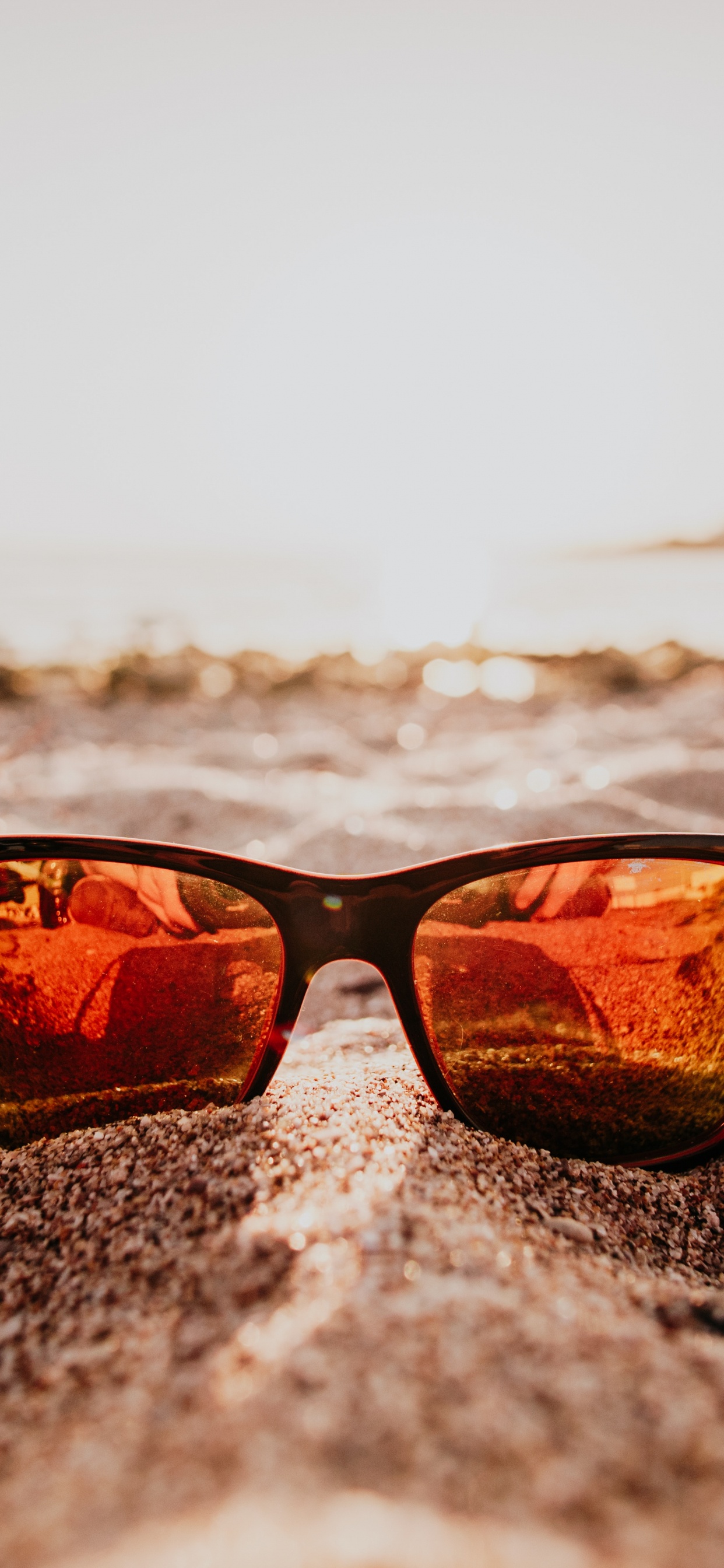 Gafas de Sol Con Montura Negra en la Playa Durante la Puesta de Sol. Wallpaper in 1242x2688 Resolution