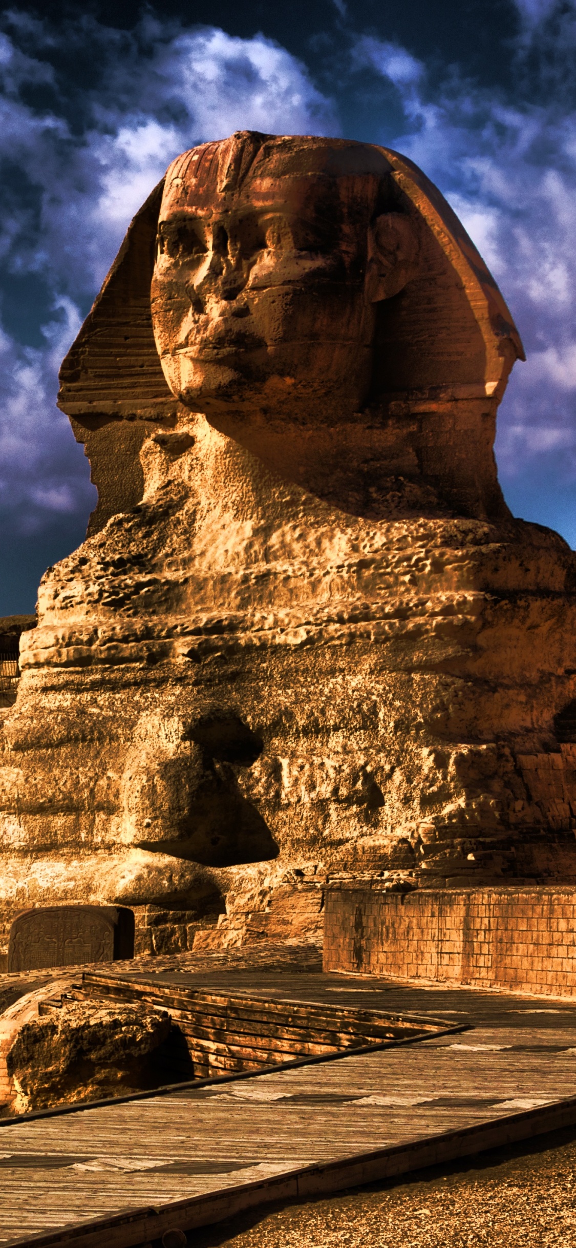 Braune Betonstatue Unter Bewölktem Himmel Tagsüber. Wallpaper in 1125x2436 Resolution