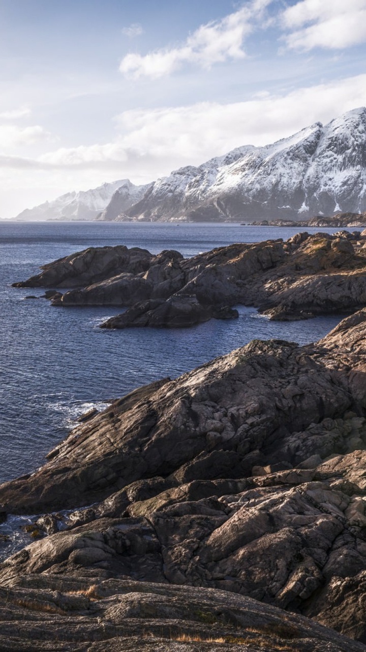 Montaña Rocosa Marrón Junto al Cuerpo de Agua Bajo el Cielo Nublado Soleado Azul y Blanco Durante el Día. Wallpaper in 720x1280 Resolution