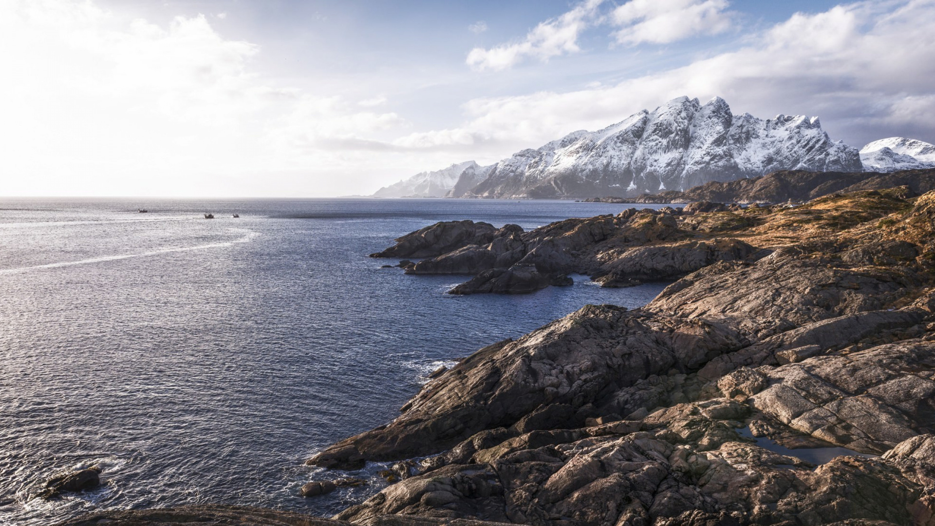 Brown Rocky Mountain Beside Body of Water Under Blue and White Sunny Cloudy Sky During Daytime. Wallpaper in 1920x1080 Resolution