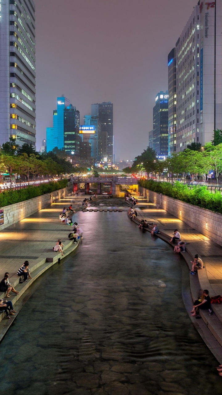 People Walking on Sidewalk Near High Rise Buildings During Night Time. Wallpaper in 720x1280 Resolution