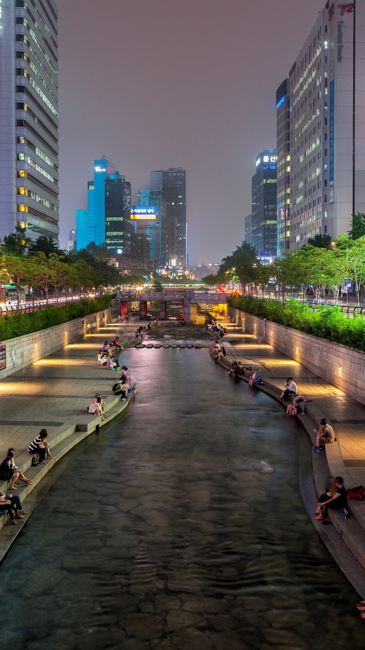 People Walking on Sidewalk Near High Rise Buildings During Night Time. Wallpaper in 750x1334 Resolution