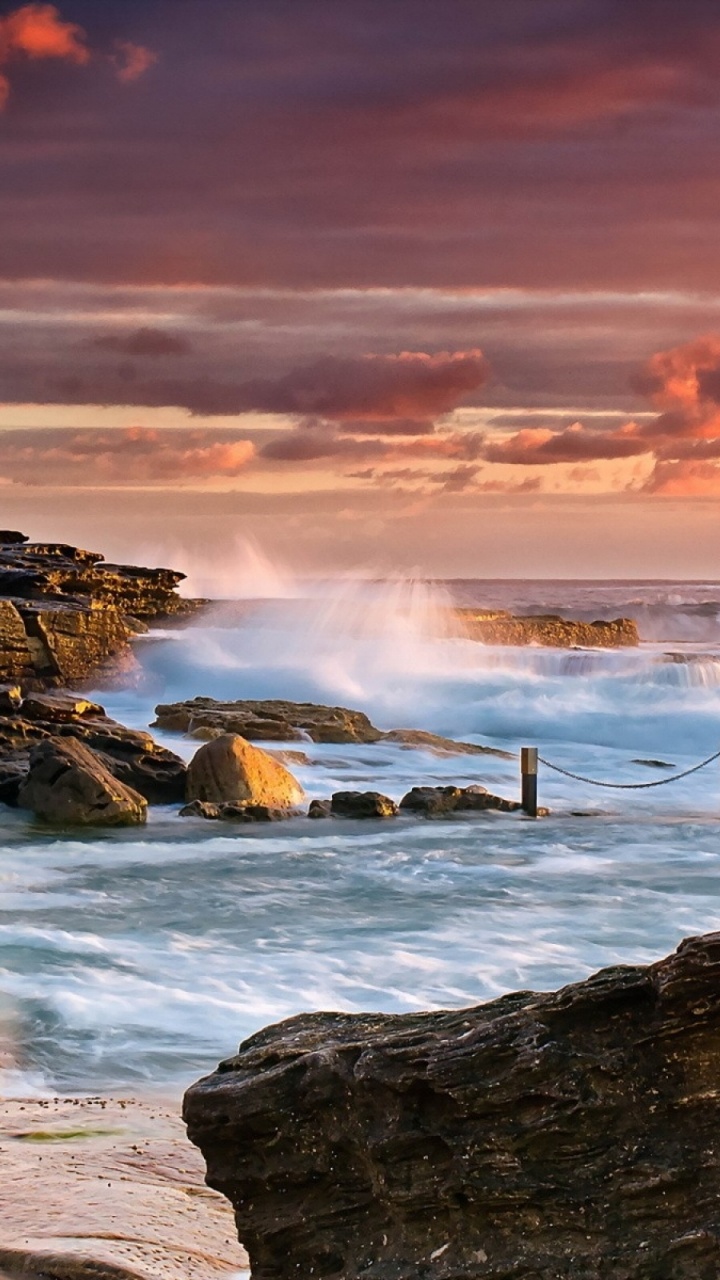 Gente de Pie Sobre la Formación Rocosa Cerca Del Mar Durante la Puesta de Sol. Wallpaper in 720x1280 Resolution