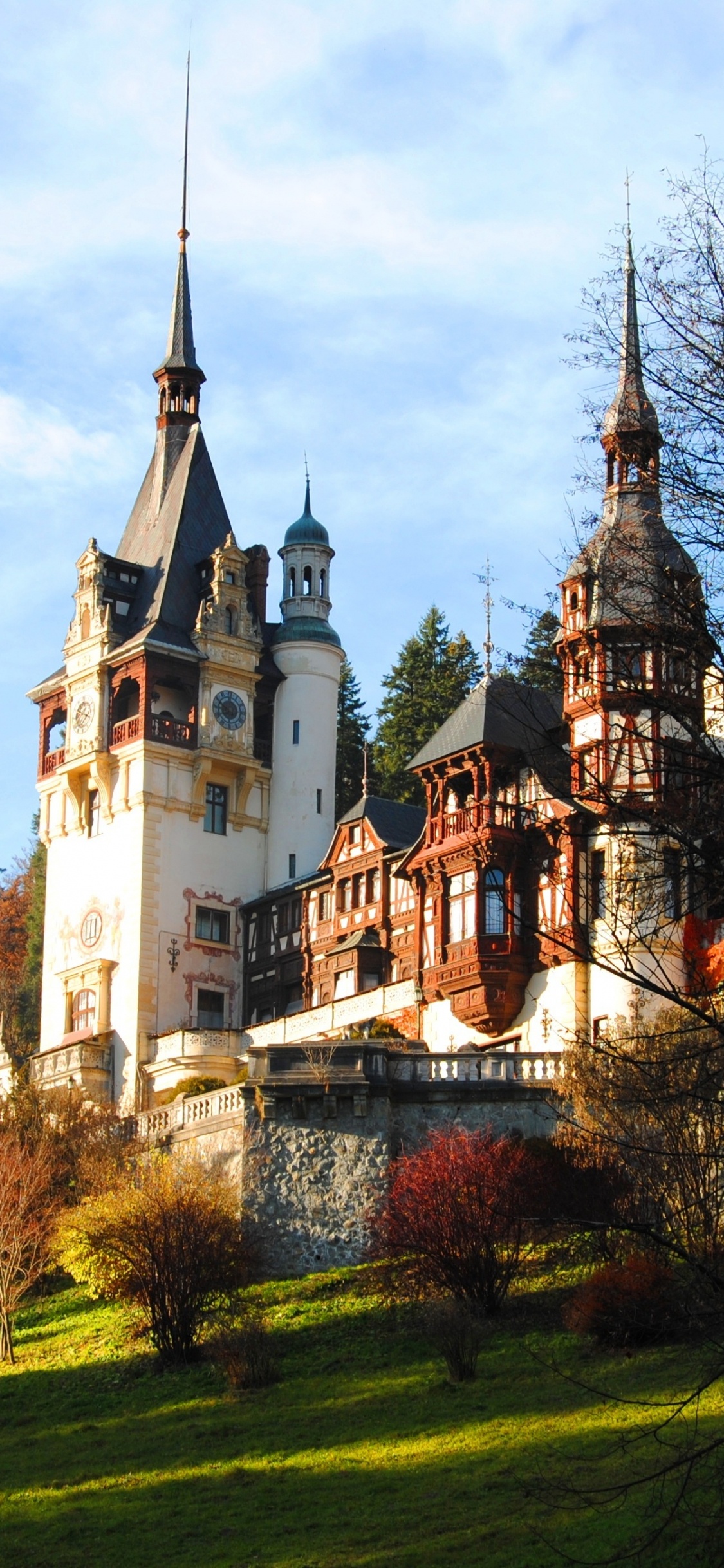 Weißes Und Braunes Betongebäude in Der Nähe Von Grünen Bäumen Unter Weißen Wolken Und Blauem Himmel Tagsüber. Wallpaper in 1125x2436 Resolution