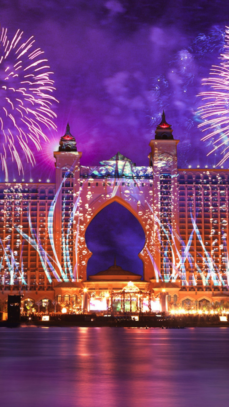 Fireworks Above City Buildings During Night Time. Wallpaper in 750x1334 Resolution