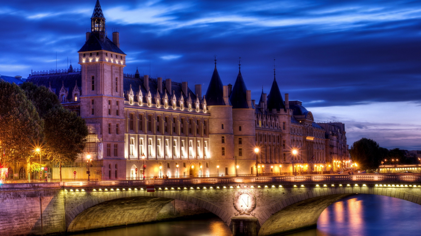 Brown Concrete Building Near River During Night Time. Wallpaper in 1366x768 Resolution