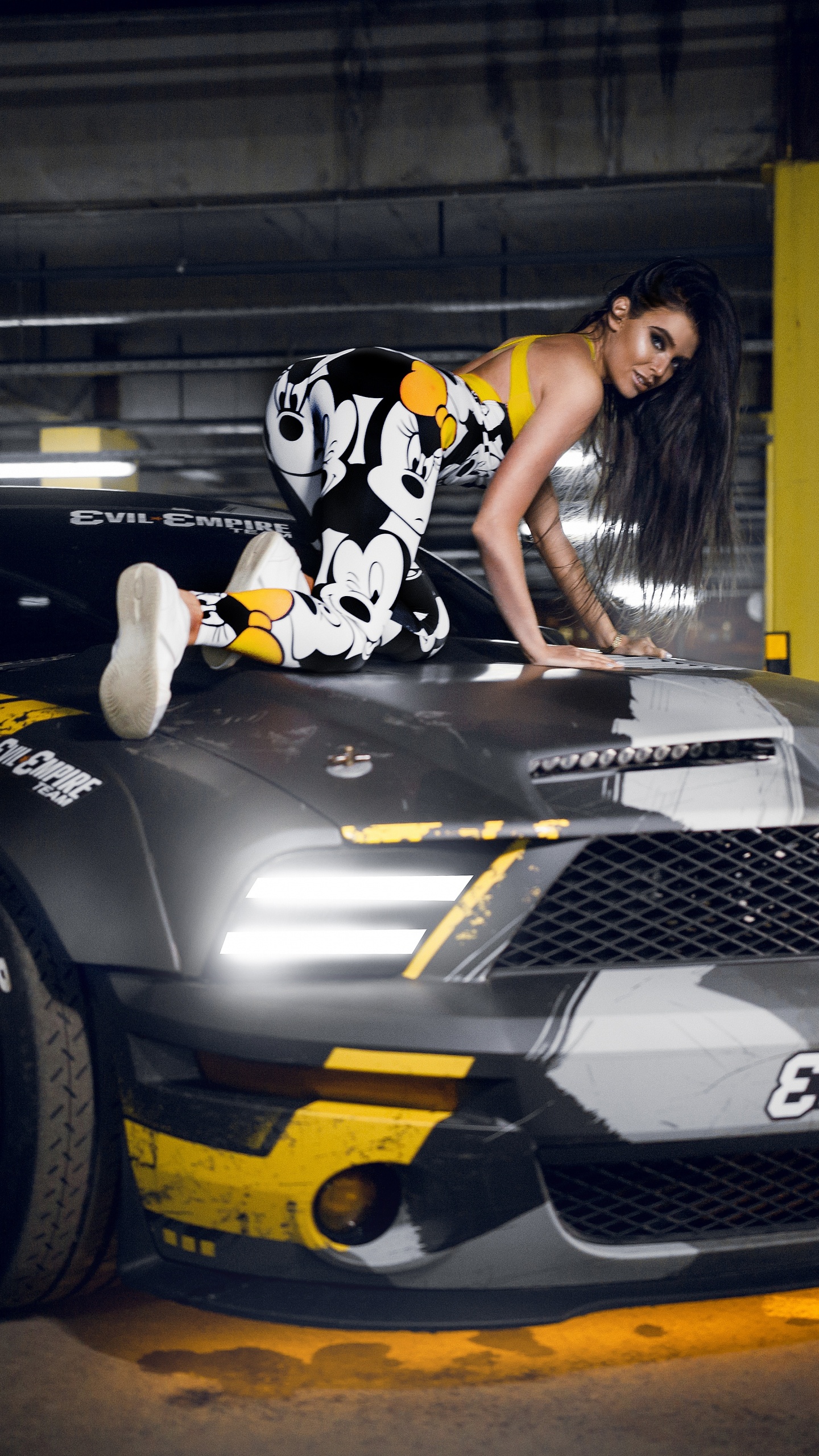 Woman in Black and White Floral Dress Riding on Black and Yellow Sports Car. Wallpaper in 1440x2560 Resolution