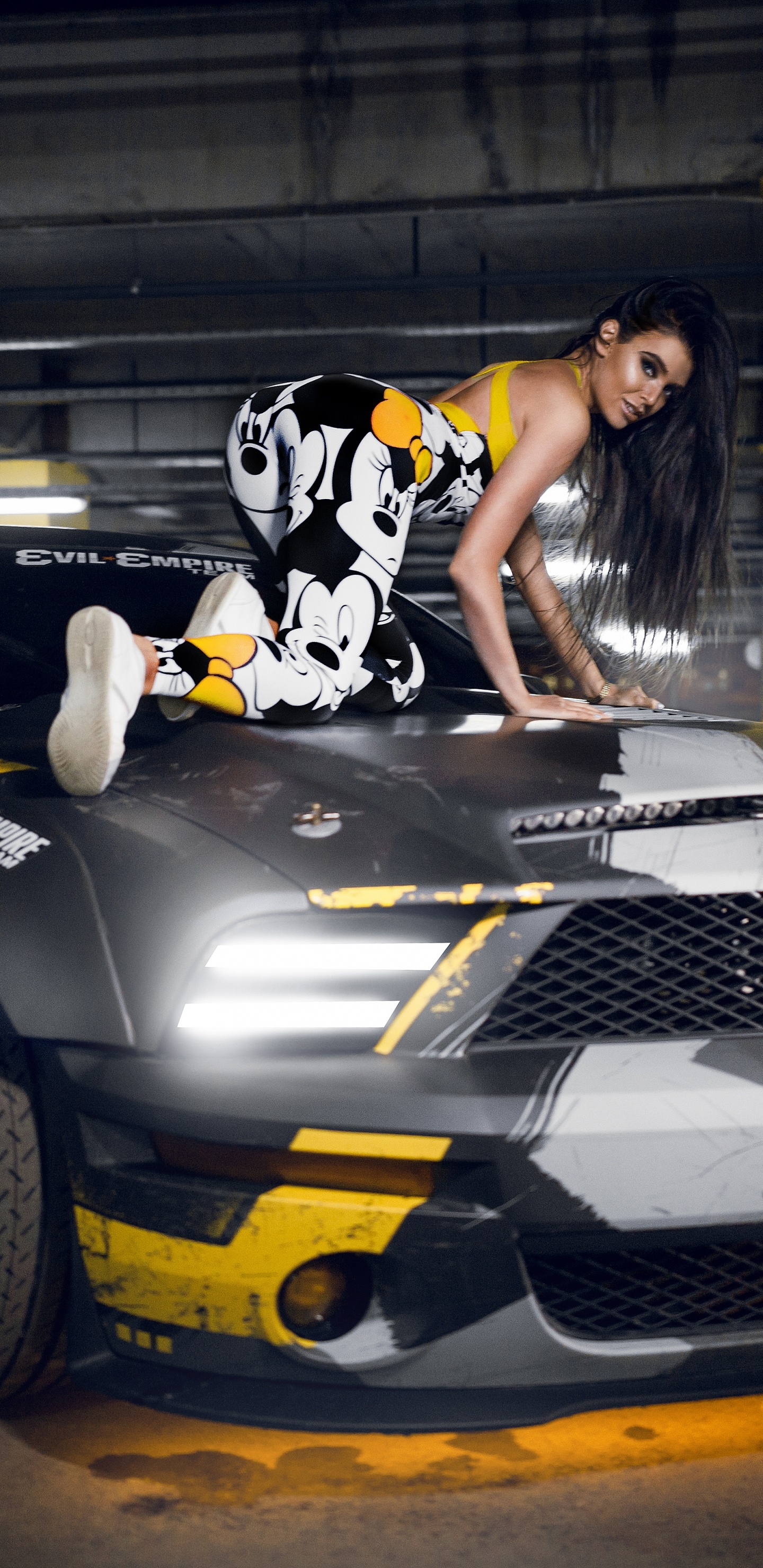 Femme en Robe à Fleurs Noir et Blanc à Cheval Sur Une Voiture de Sport Noir et Jaune. Wallpaper in 1440x2960 Resolution