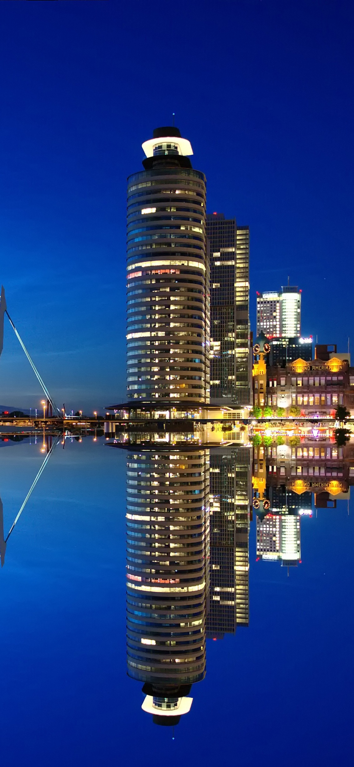 Bridge Over Water Near City Buildings During Night Time. Wallpaper in 1125x2436 Resolution