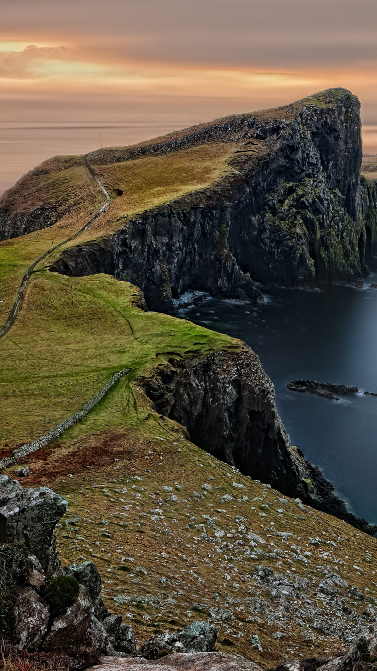 Green Grass Covered Mountain Beside Body of Water During Daytime. Wallpaper in 750x1334 Resolution