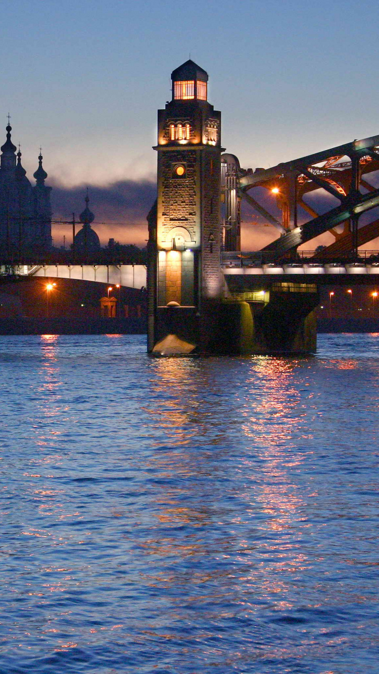 Brown Concrete Bridge Over Body of Water During Night Time. Wallpaper in 750x1334 Resolution