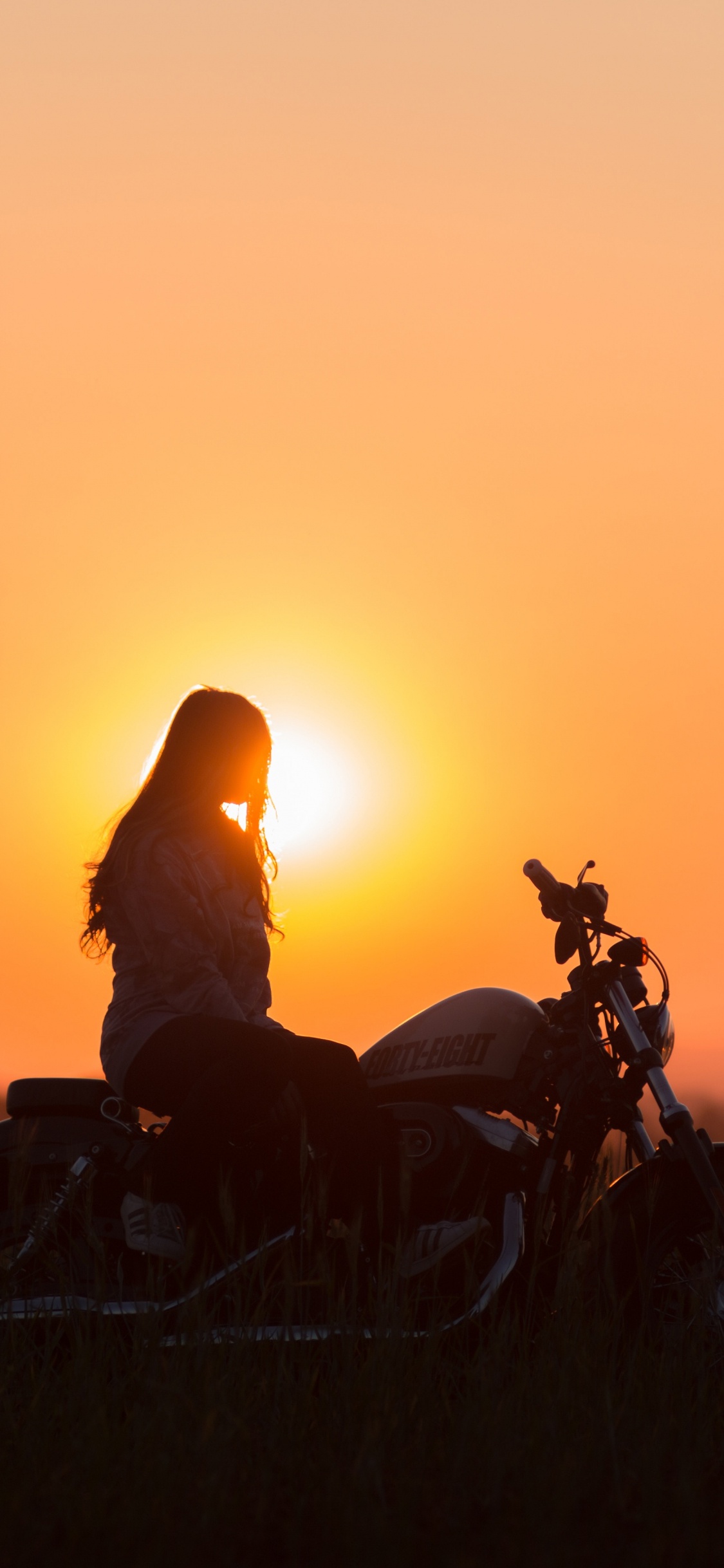 Silhouette Eines Mannes, Der Während Des Sonnenuntergangs Motorrad Fährt. Wallpaper in 1125x2436 Resolution