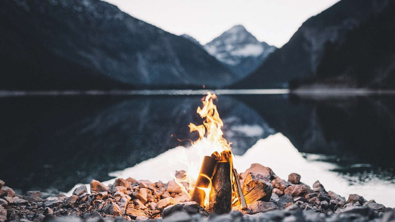 Bonfire on Rocky Shore Near Lake During Daytime. Wallpaper in 1280x720 Resolution
