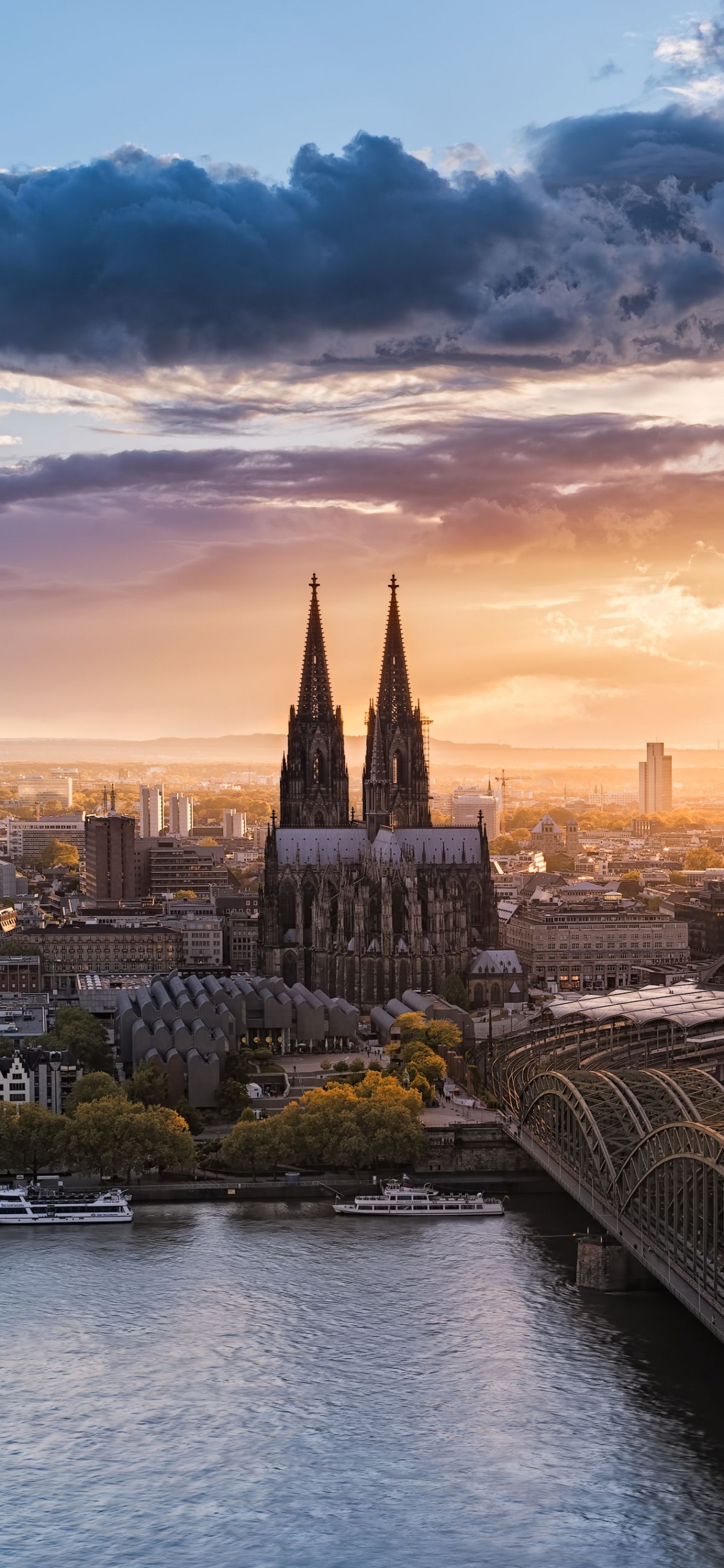 Puente Sobre el Río Cerca de Los Edificios de la Ciudad Durante la Puesta de Sol. Wallpaper in 1125x2436 Resolution