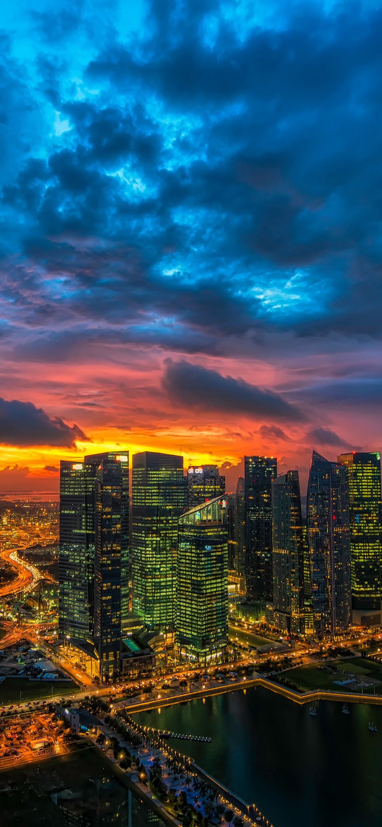 Skyline Der Stadt Unter Blauem Und Orangefarbenem Bewölktem Himmel Während Der Nacht. Wallpaper in 1242x2688 Resolution