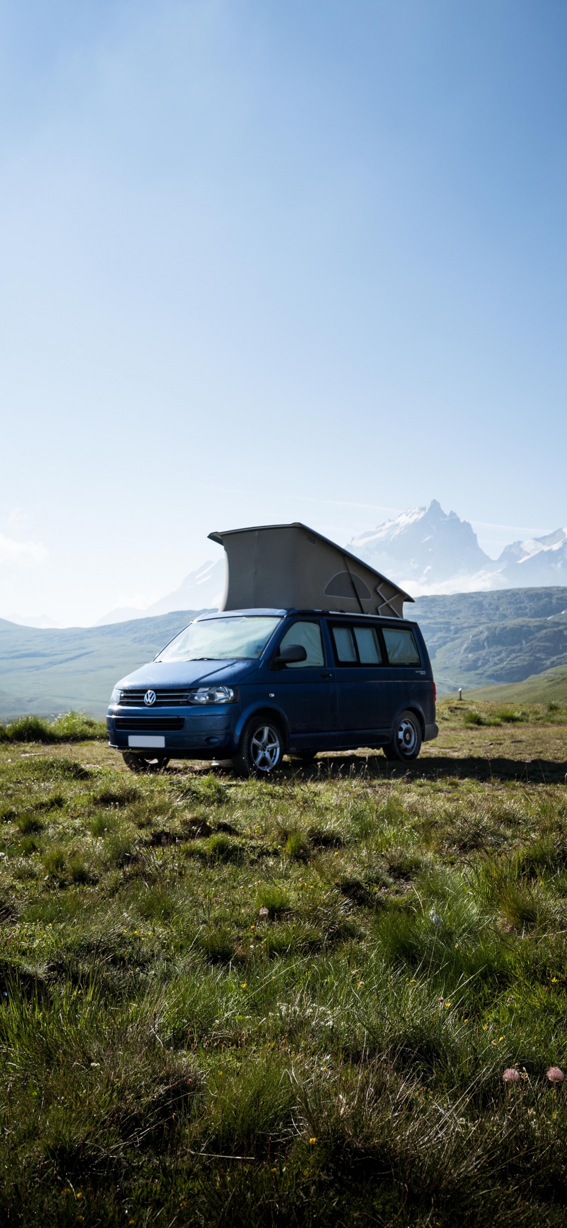 Suv Bleu Sur Champ D'herbe Verte Près de la Montagne Pendant la Journée. Wallpaper in 1125x2436 Resolution