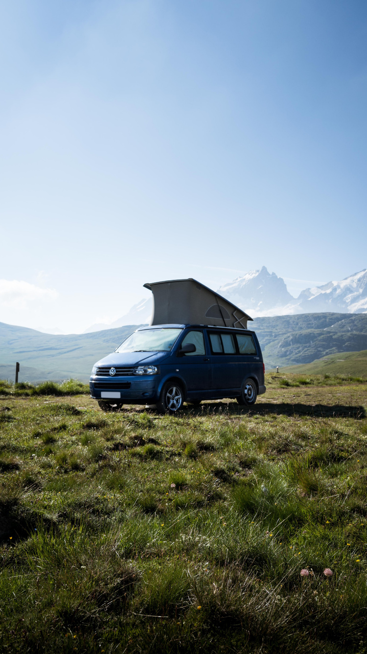 Suv Bleu Sur Champ D'herbe Verte Près de la Montagne Pendant la Journée. Wallpaper in 750x1334 Resolution