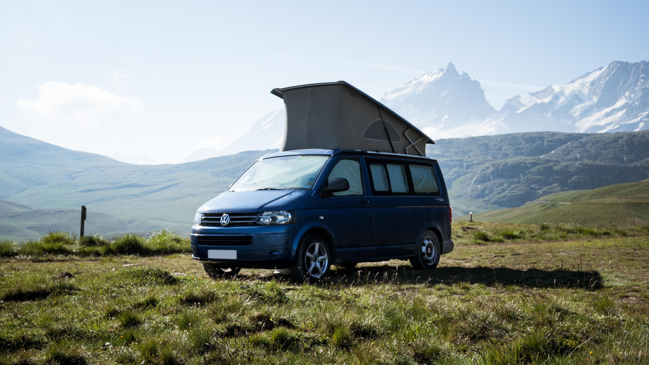 Blue Suv on Green Grass Field Near Mountain During Daytime. Wallpaper in 2560x1440 Resolution