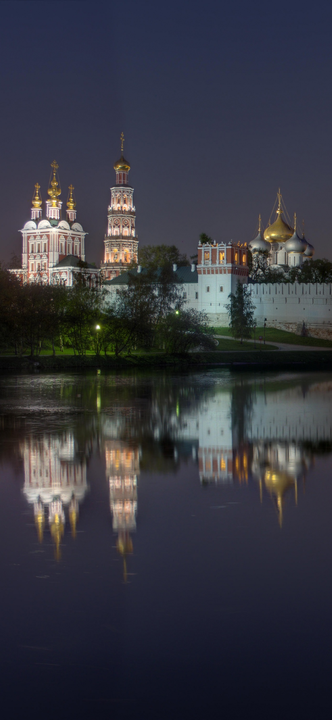 Gewässer in Der Nähe Von Stadtgebäuden Während Der Nacht. Wallpaper in 1125x2436 Resolution