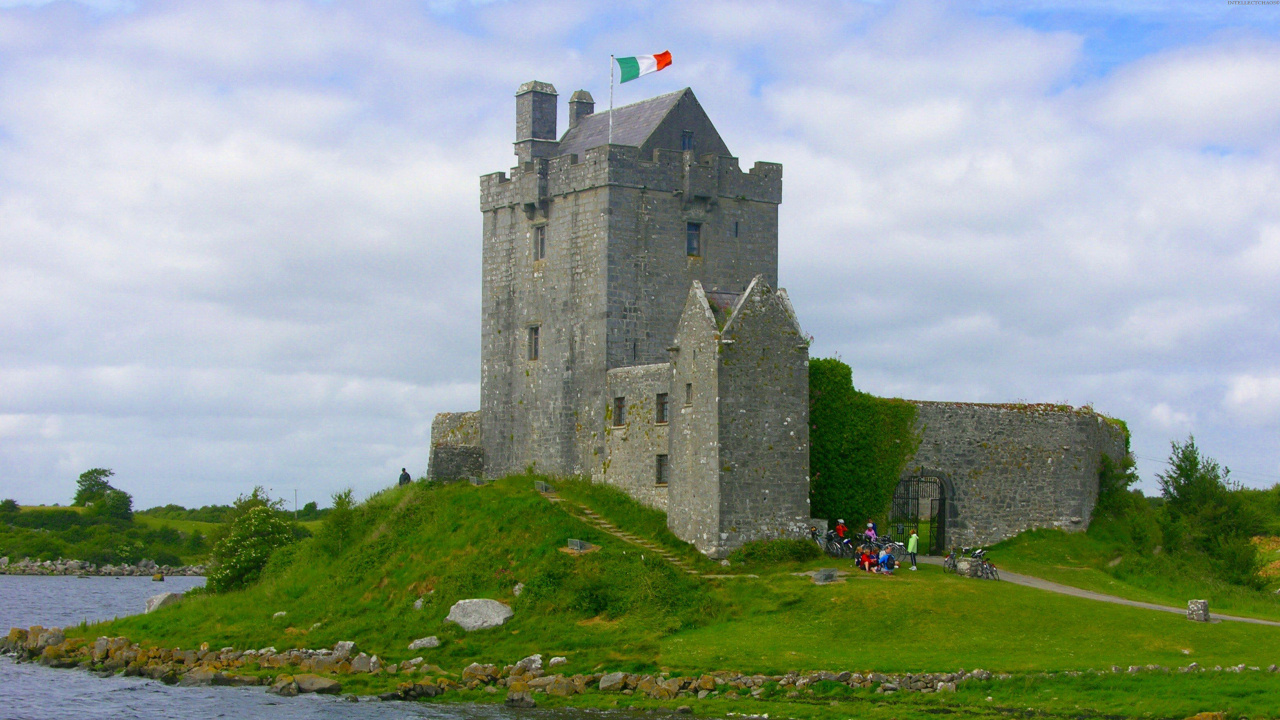 Grey Concrete Building Near Green Grass Field Under White Clouds During Daytime. Wallpaper in 1280x720 Resolution