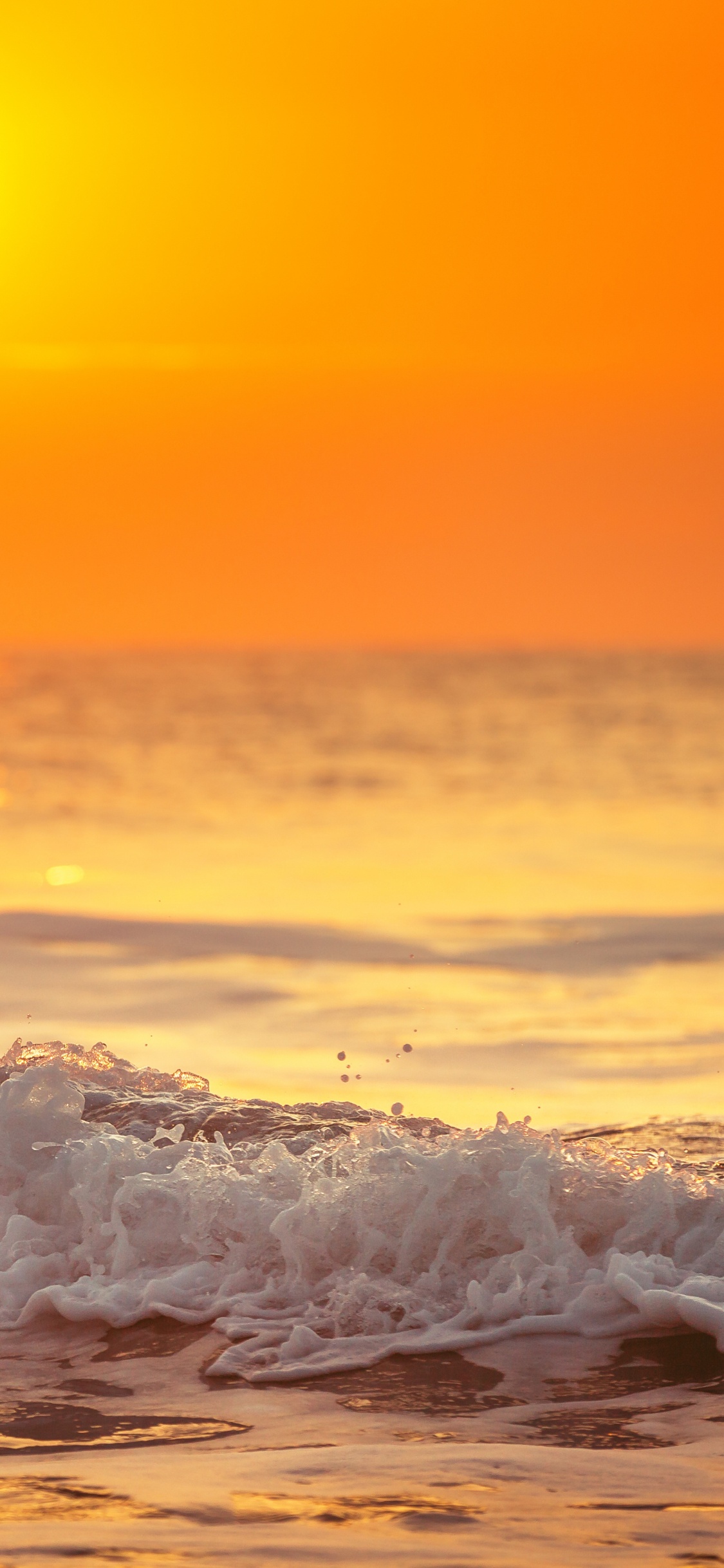 Ocean Waves Crashing on Shore During Sunset. Wallpaper in 1125x2436 Resolution