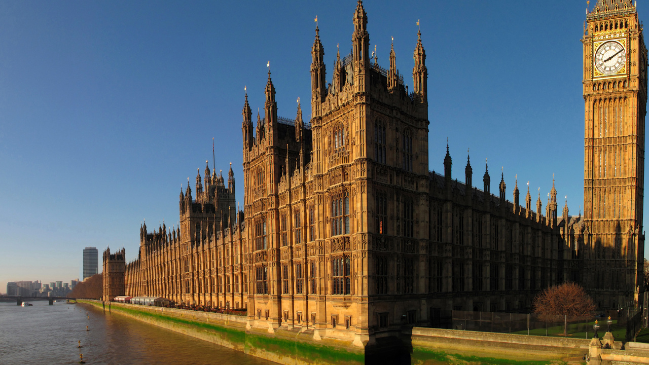 Brown Concrete Building Near Body of Water During Daytime. Wallpaper in 1280x720 Resolution