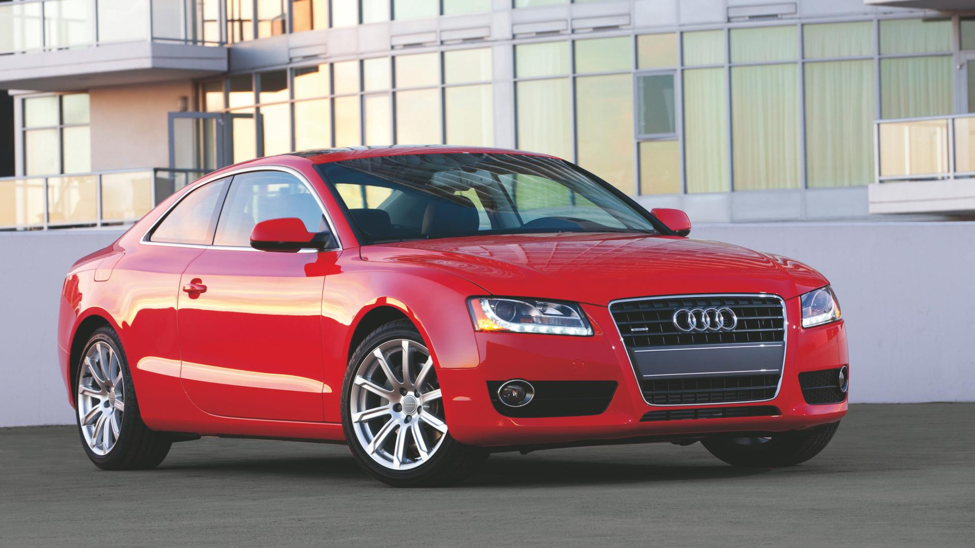 Audi a 4 Sedán Rojo Estacionado Cerca Del Edificio Blanco Durante el Día. Wallpaper in 1920x1080 Resolution