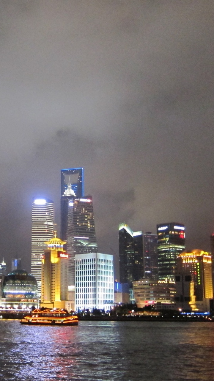 Skyline Der Stadt Über Gewässer Während Der Nacht. Wallpaper in 720x1280 Resolution