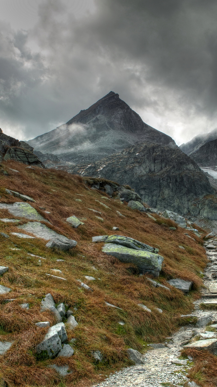 Green Grass Field Near Mountain Under Cloudy Sky During Daytime. Wallpaper in 750x1334 Resolution