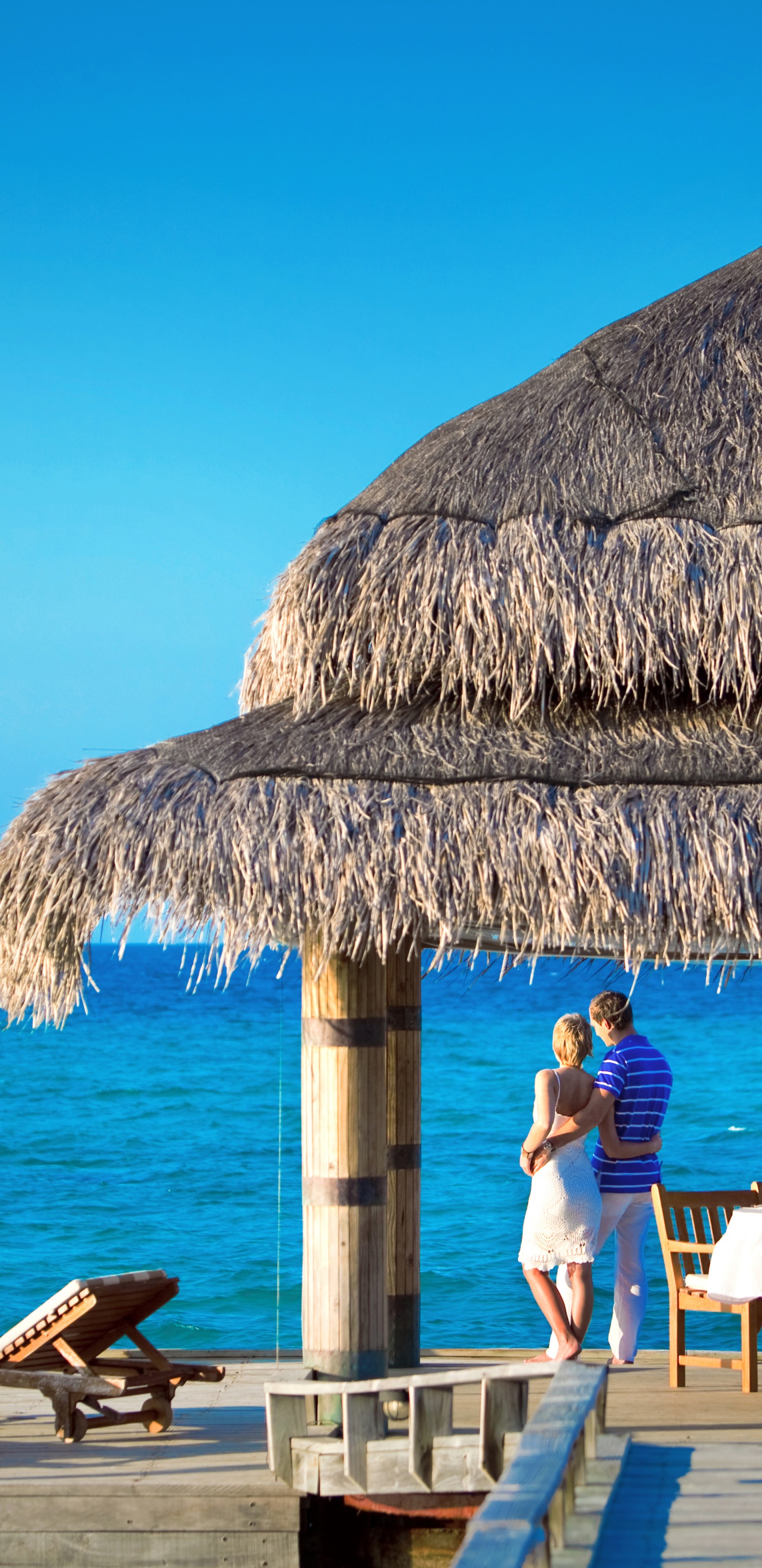 People Sitting on Brown Wooden Chairs Near Brown Nipa Hut During Daytime. Wallpaper in 1440x2960 Resolution