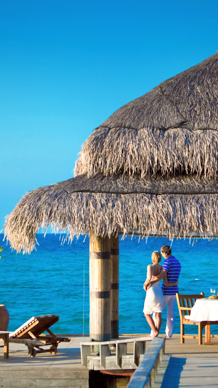 People Sitting on Brown Wooden Chairs Near Brown Nipa Hut During Daytime. Wallpaper in 750x1334 Resolution