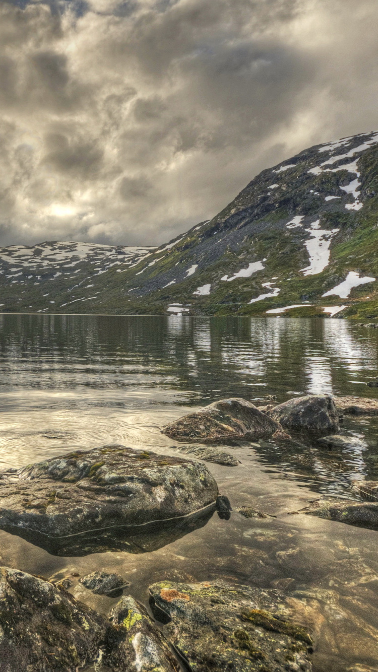 Brown Wooden House on Rocky Shore Near Mountain Under Cloudy Sky During Daytime. Wallpaper in 750x1334 Resolution