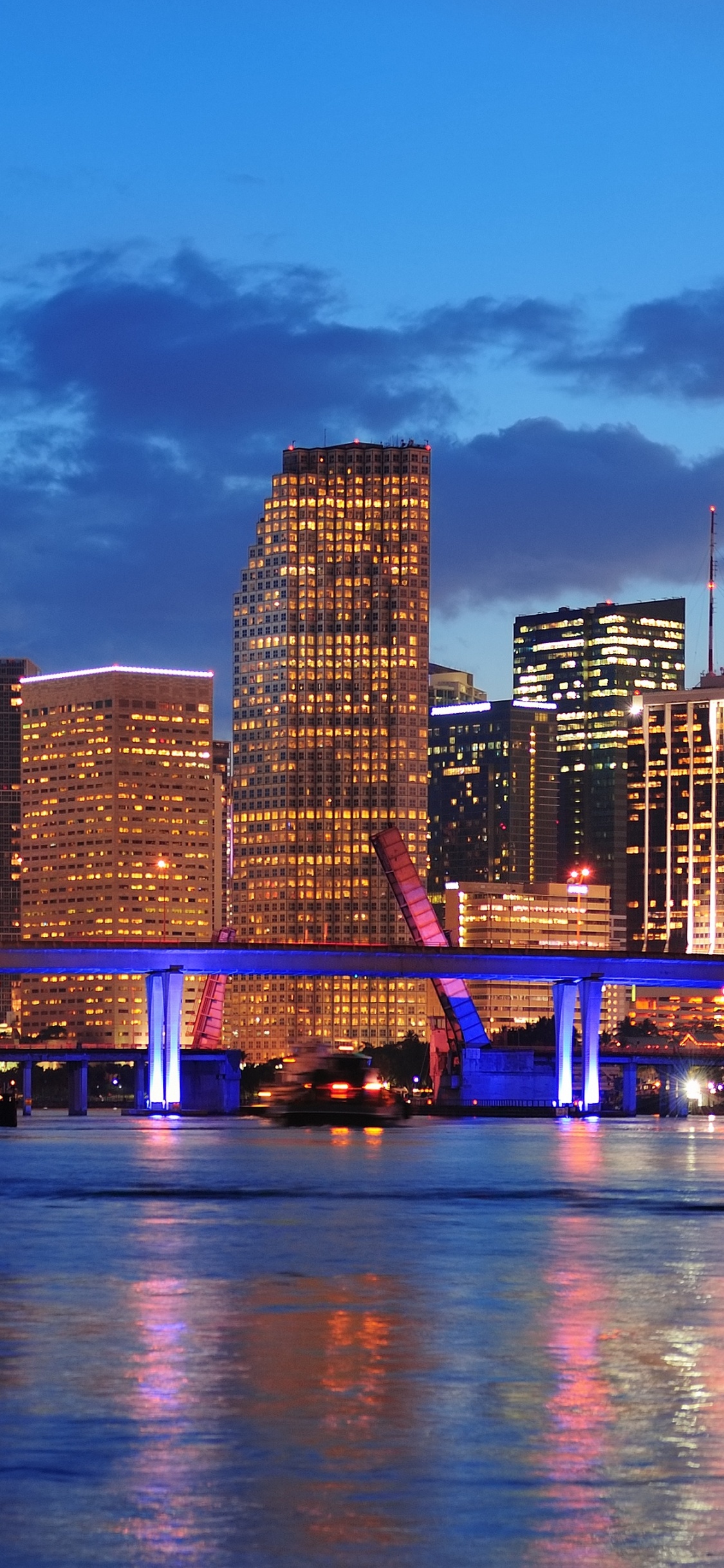 City Skyline Across Body of Water During Night Time. Wallpaper in 1125x2436 Resolution