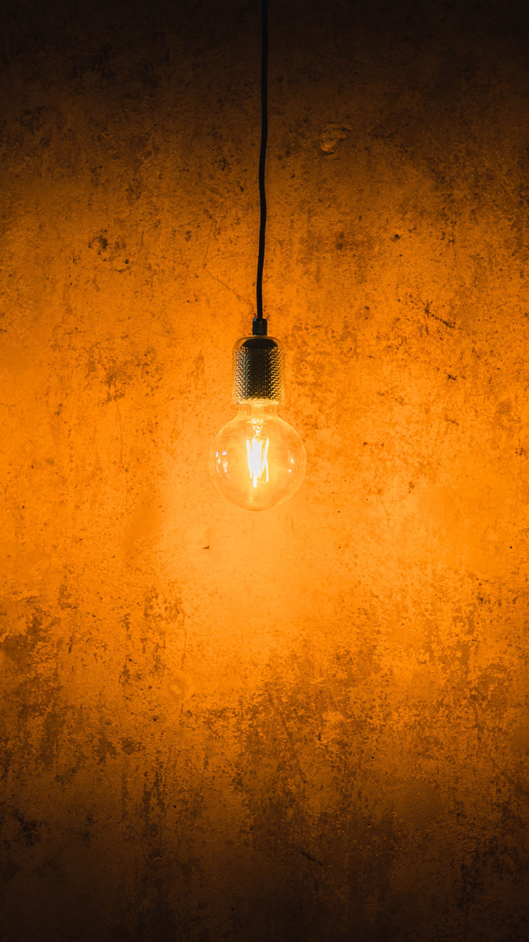 White Light Bulb Turned on on Orange Wall. Wallpaper in 750x1334 Resolution