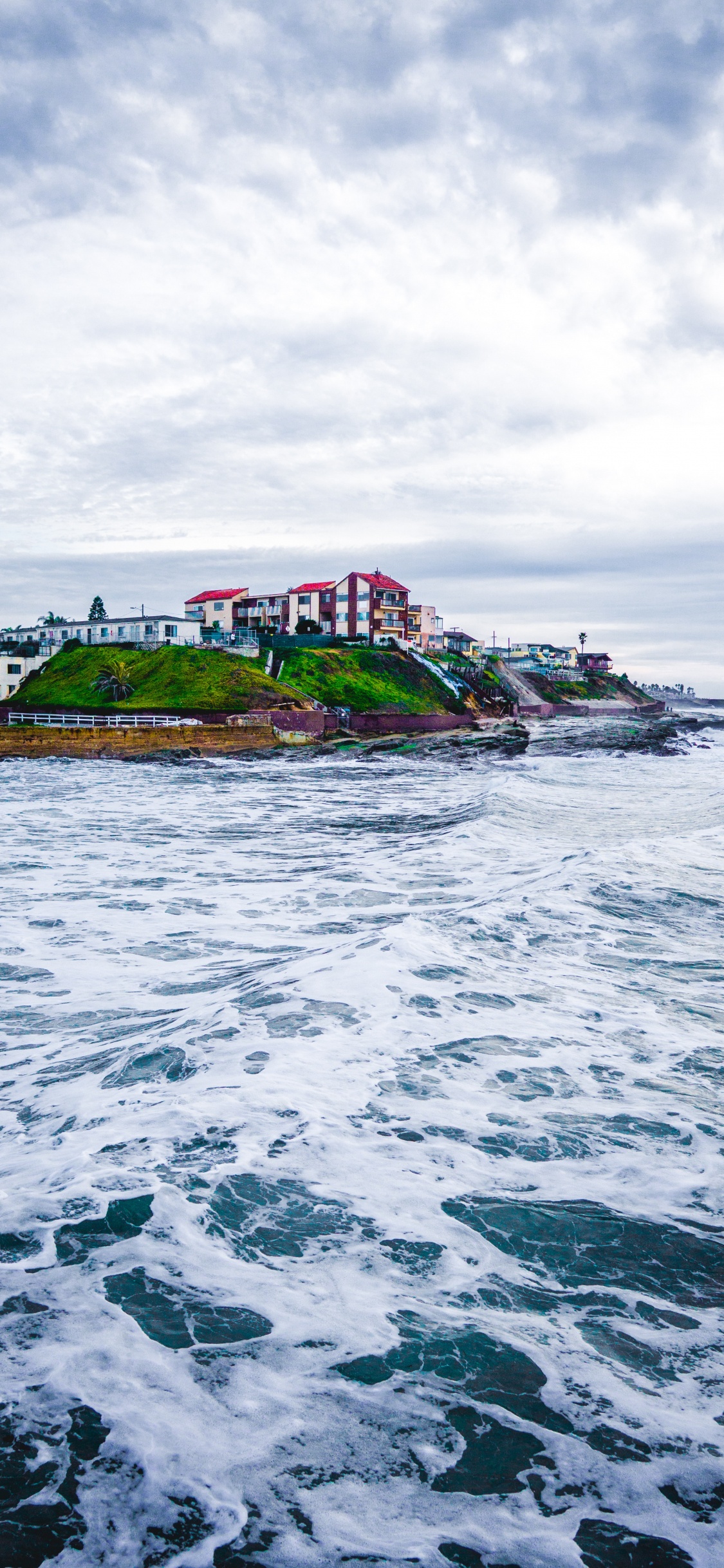 Edificio de Hormigón Blanco Cerca Del Cuerpo de Agua Durante el Día. Wallpaper in 1125x2436 Resolution