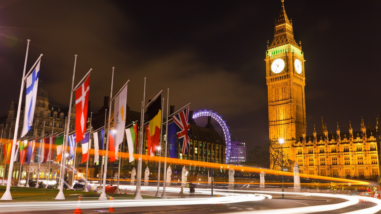 Brown Concrete Building With Flags During Nighttime. Wallpaper in 1280x720 Resolution
