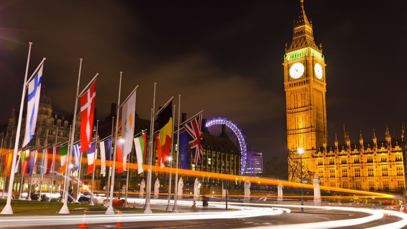 Brown Concrete Building With Flags During Nighttime. Wallpaper in 1366x768 Resolution
