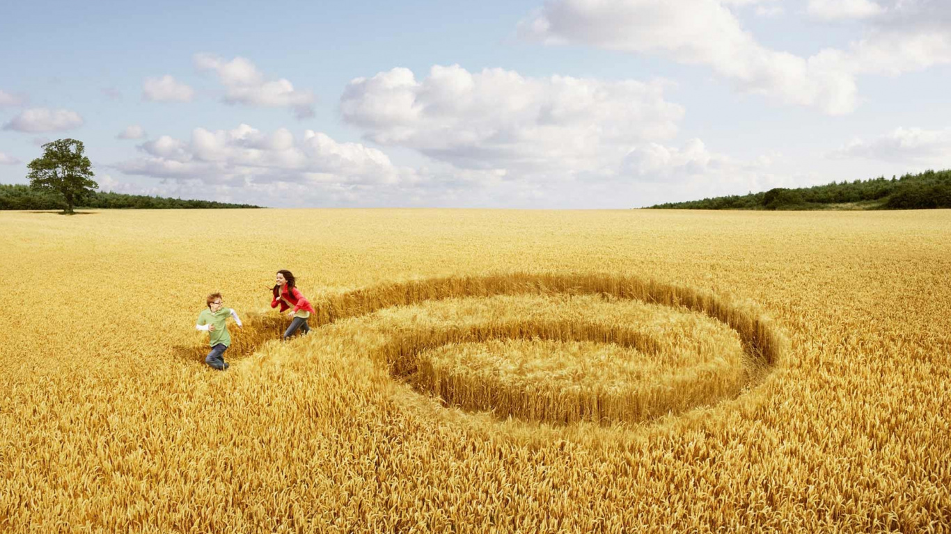 2 People Sitting on Green Grass Field Under White Clouds and Blue Sky During Daytime. Wallpaper in 1366x768 Resolution
