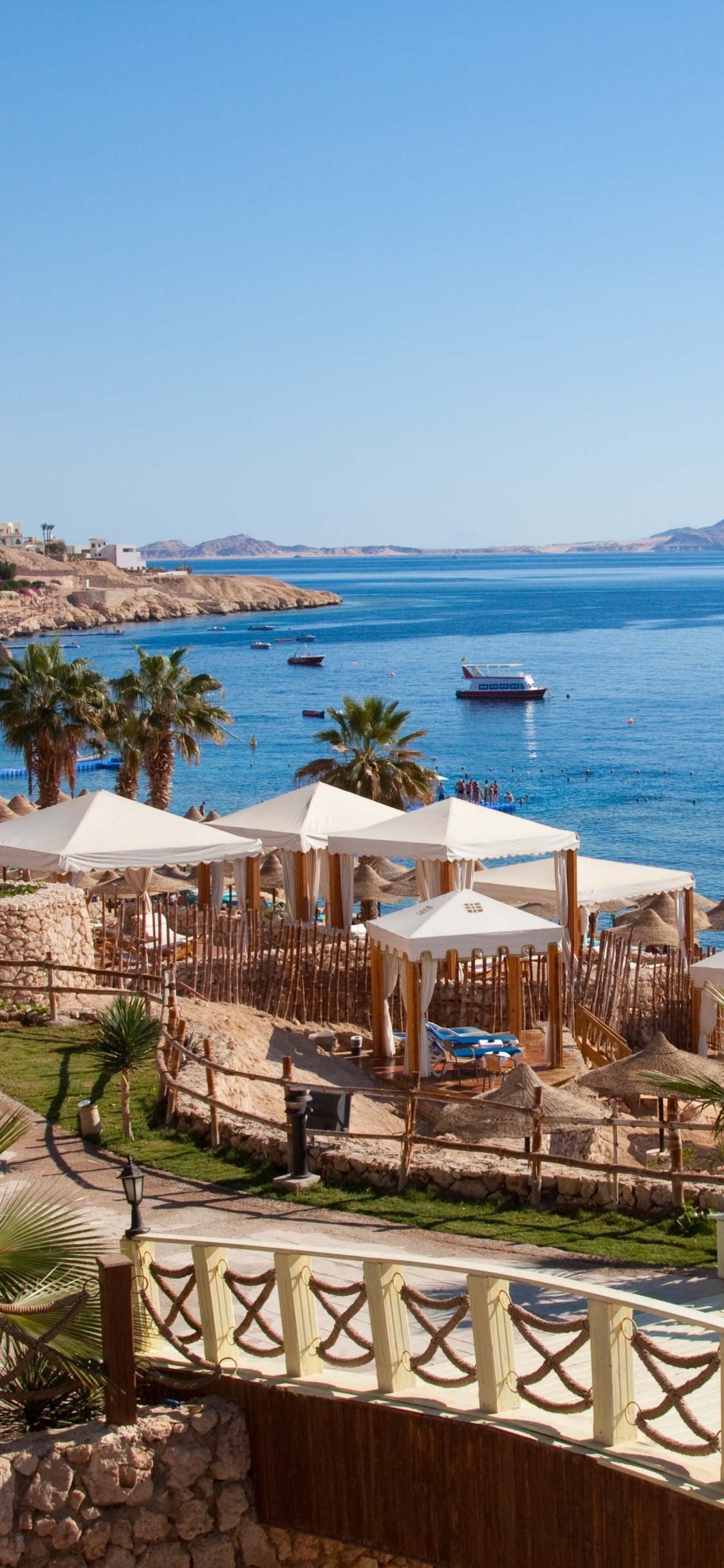 White and Brown Concrete Building Near Body of Water During Daytime. Wallpaper in 1125x2436 Resolution