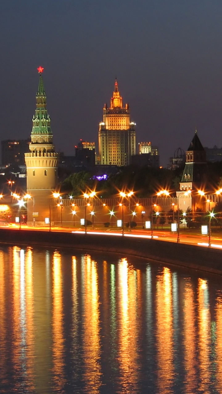 Lighted City Buildings Near Body of Water During Night Time. Wallpaper in 720x1280 Resolution