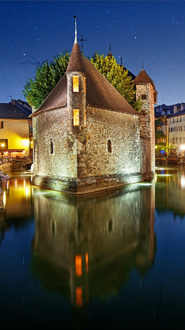 Brown Concrete Building Near Body of Water During Night Time. Wallpaper in 750x1334 Resolution