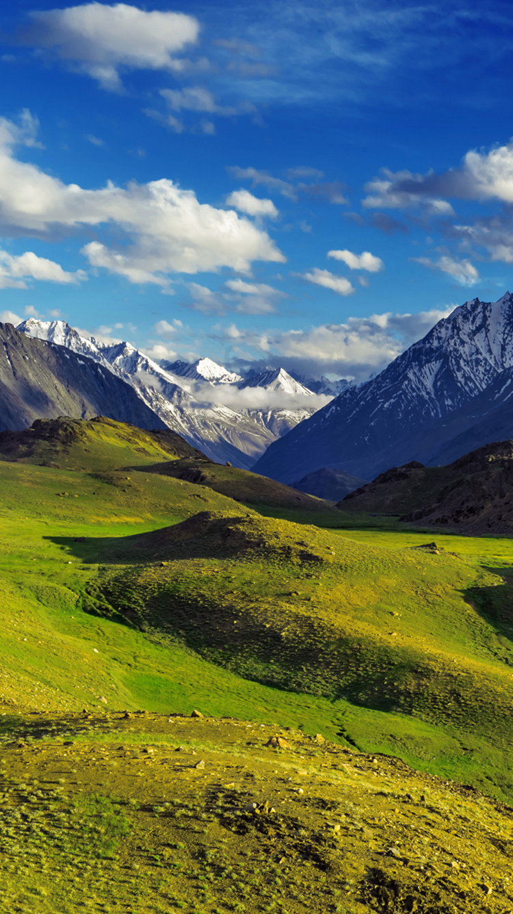 Green Grass Field Near Mountains Under Blue Sky During Daytime. Wallpaper in 750x1334 Resolution