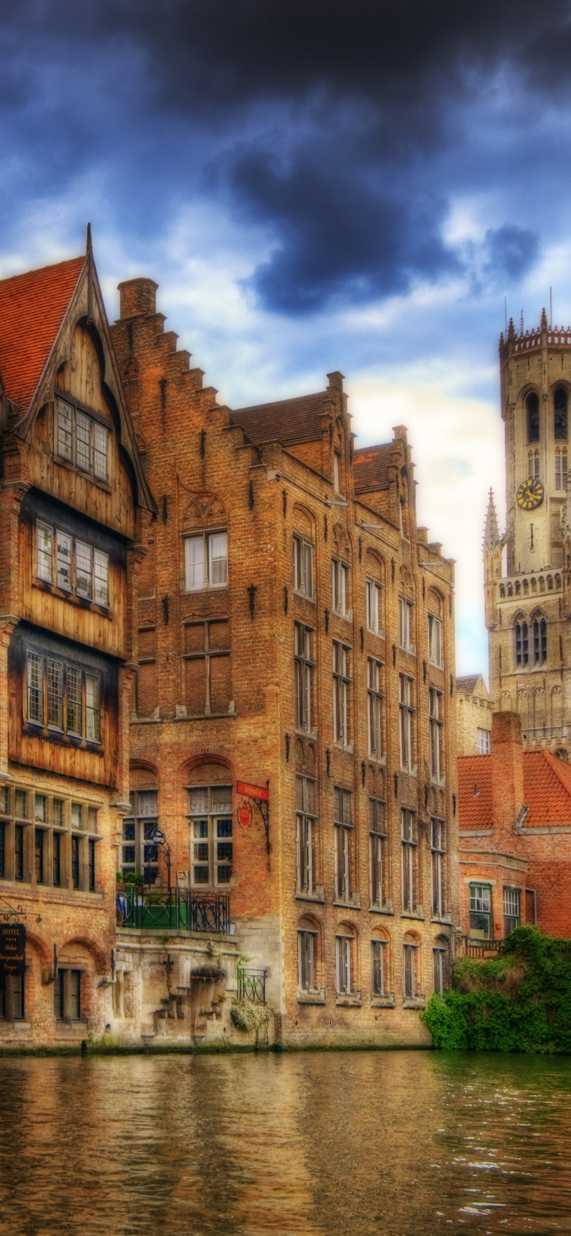 Brown Concrete Building Beside River During Daytime. Wallpaper in 1125x2436 Resolution