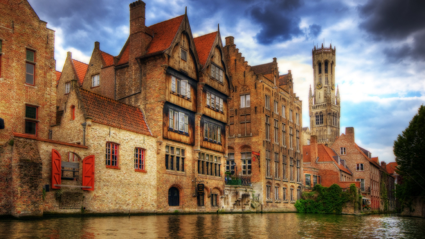 Brown Concrete Building Beside River During Daytime. Wallpaper in 1366x768 Resolution