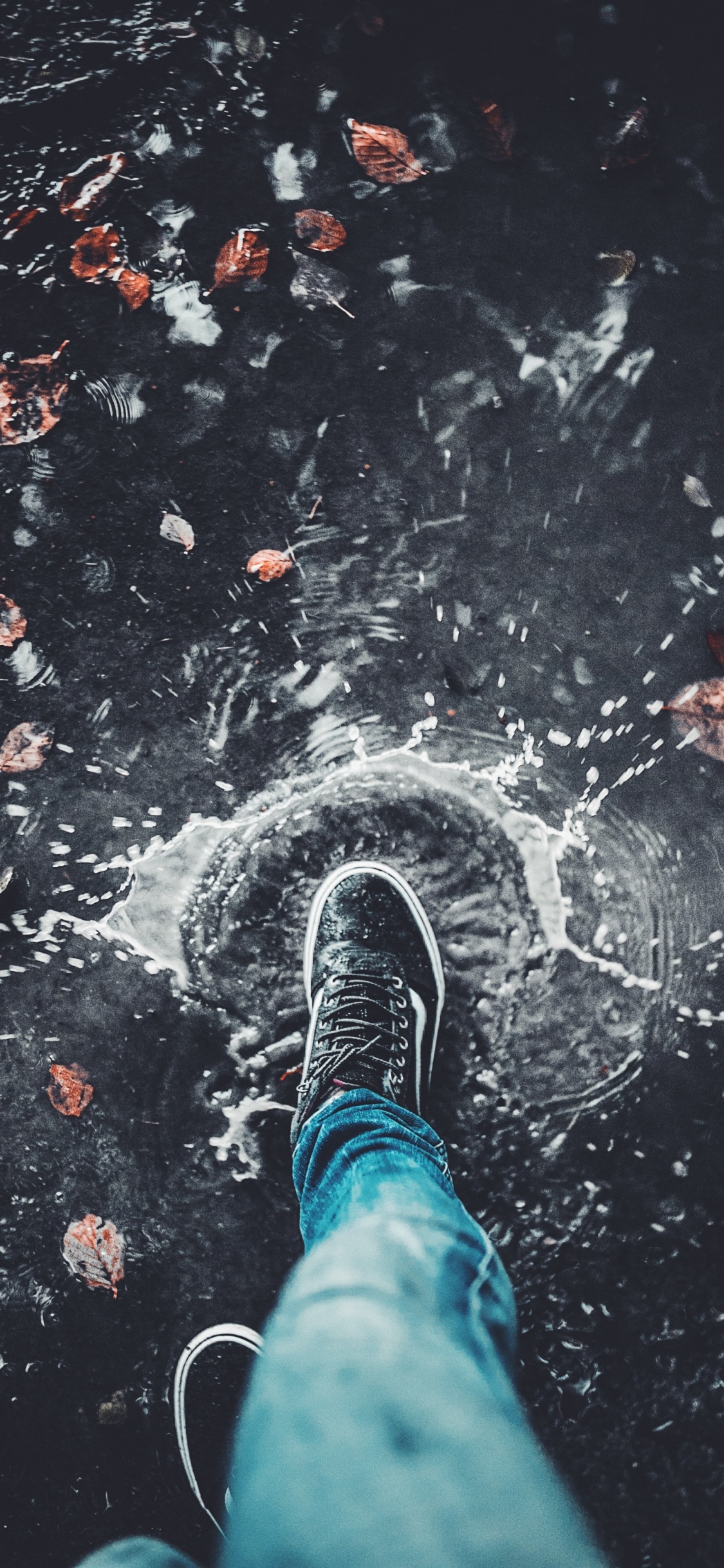 Persona en Jeans Azul y Zapatillas Blancas y Negras de Pie Sobre el Agua. Wallpaper in 1125x2436 Resolution