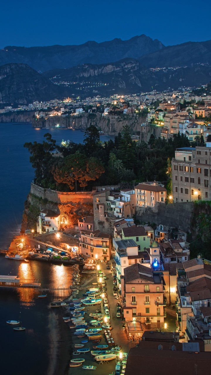 Aerial View of City Buildings Near Body of Water During Night Time. Wallpaper in 720x1280 Resolution