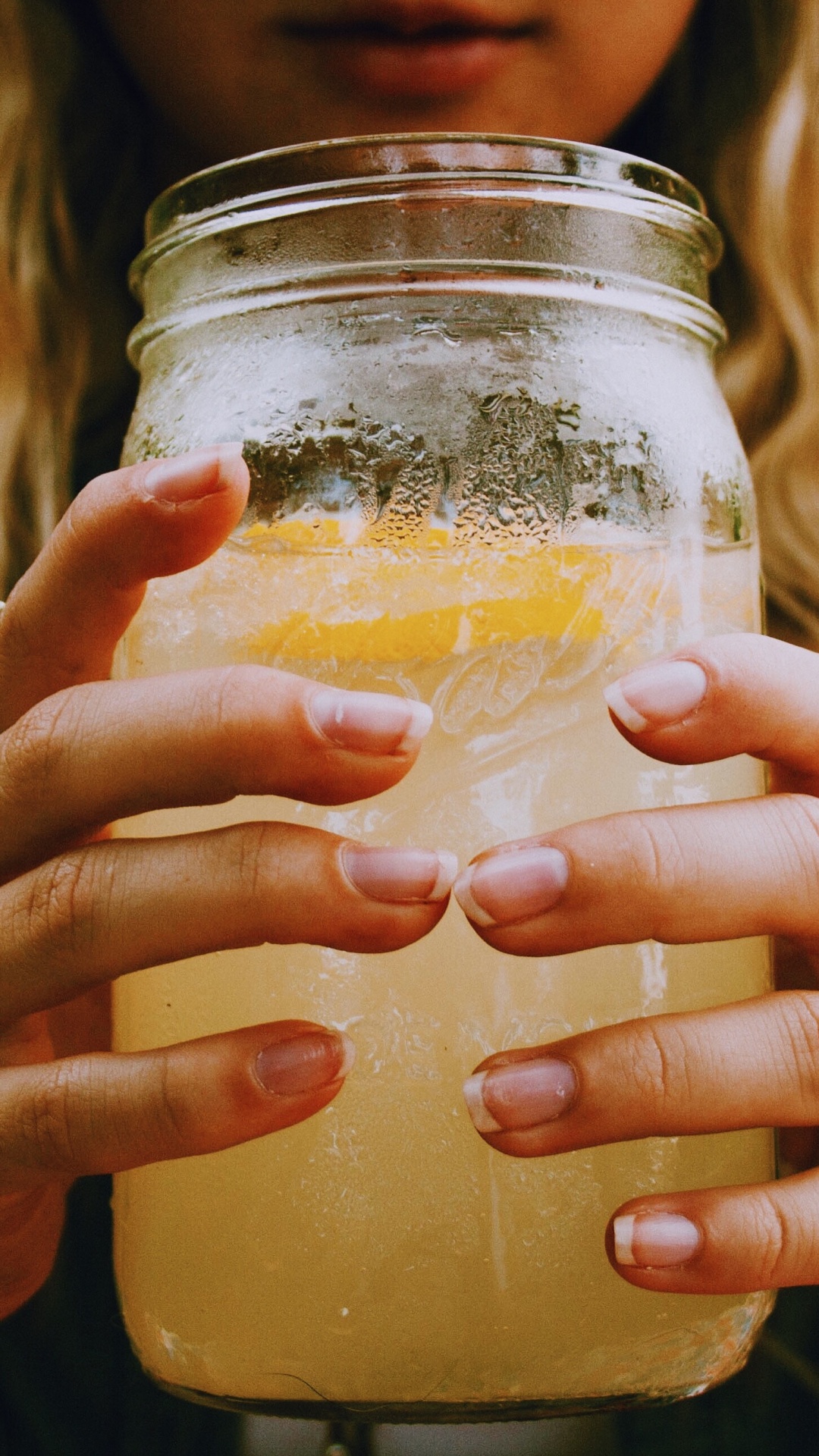 Woman Holding Clear Glass Jar With Yellow Liquid. Wallpaper in 1080x1920 Resolution